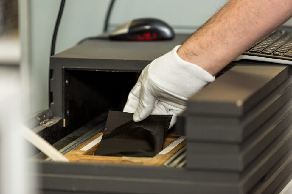 Gloved hand loading a microfiche card into a Stor-a-File scanner